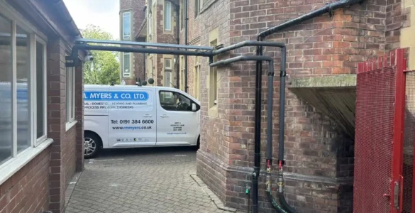 Parked plumbing services van in narrow alleyway.